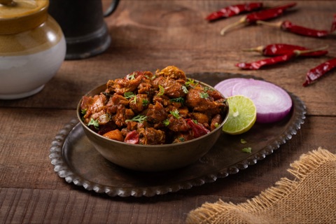 Spiced pieces garnished with herbs beside lime and onion