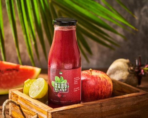 A bottle of red fruit juice with watermelon, apple and lime