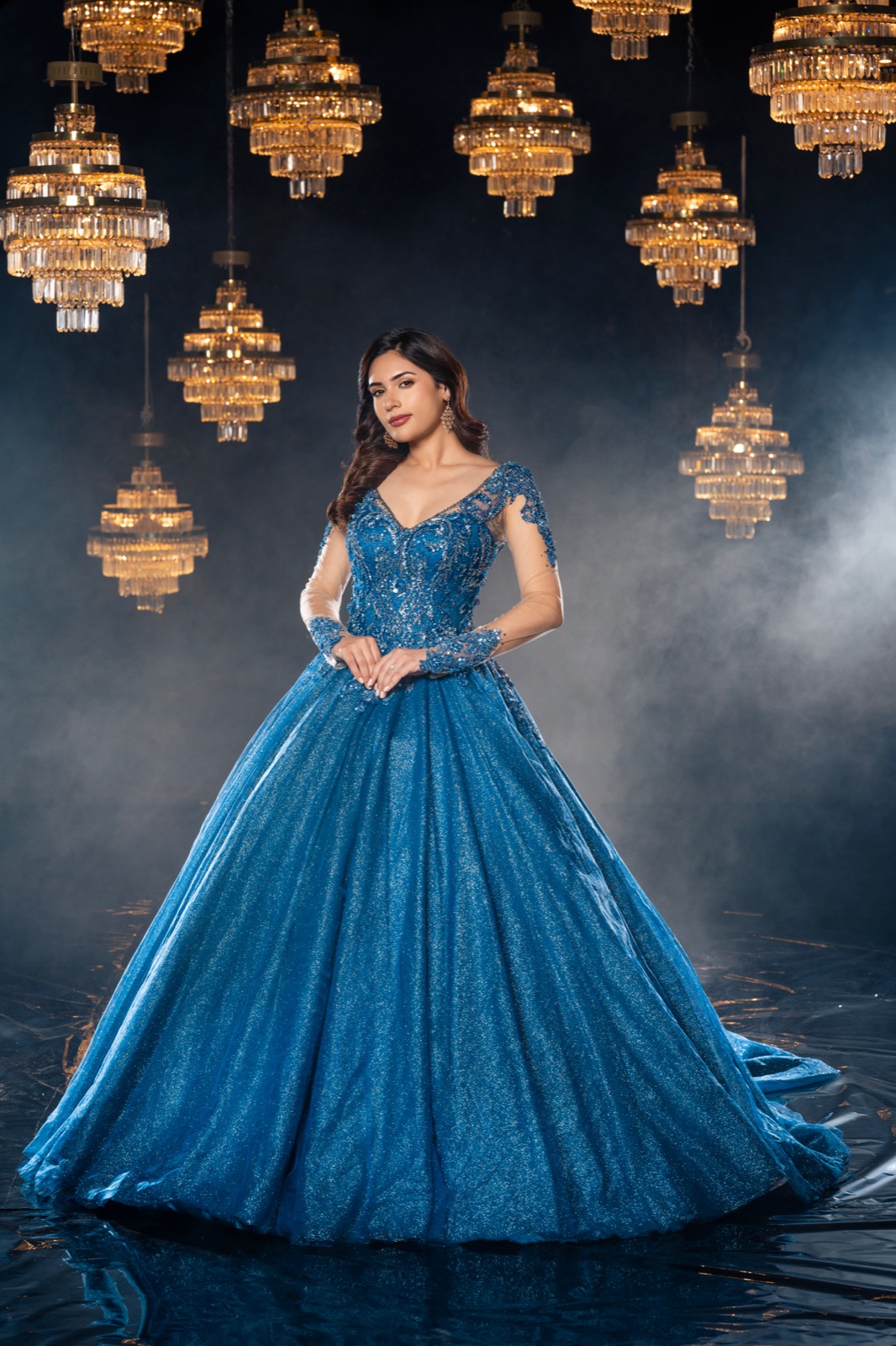 Fashion portrait in a blue gown beneath golden chandeliers, photographed by Suraj Desur