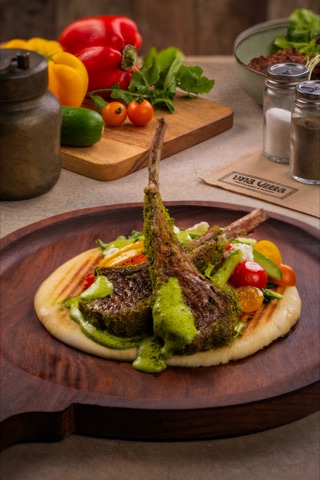 Grilled chops with vegetables and green sauce on a round board
