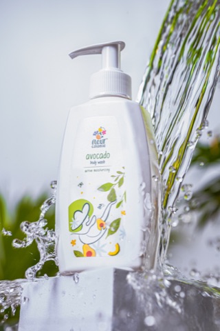 White pump bottle beside splashing water and green foliage