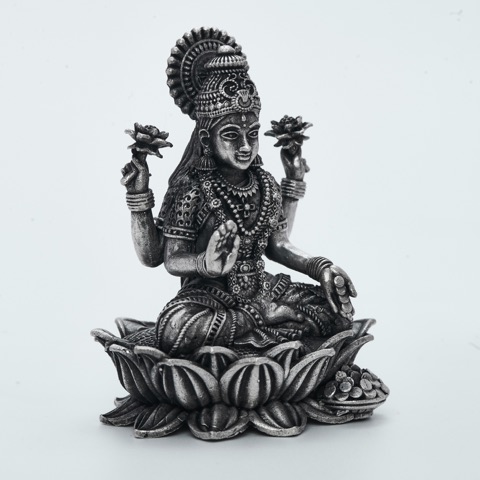 Decorative metal figure seated on a lotus-shaped base