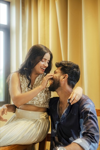Woman playfully touching a seated man's face by a window