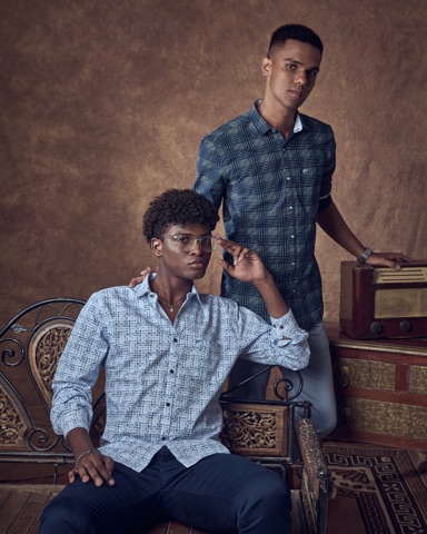 Two men in blue shirts posed with an ornate chair