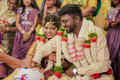 Couple wearing flower garlands and smiling during a wedding ceremony