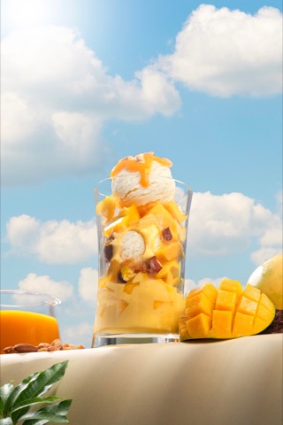 Mango dessert layered in a tall glass against a blue sky backdrop