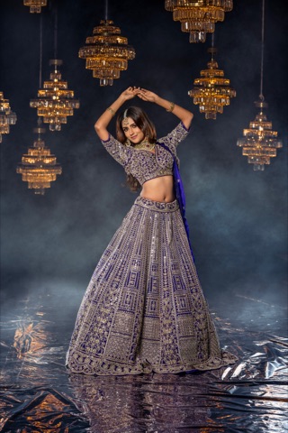 Woman in an embroidered purple outfit beneath golden chandeliers