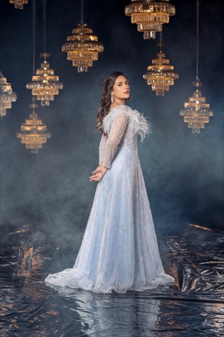 Woman in a pale evening gown beneath golden chandeliers