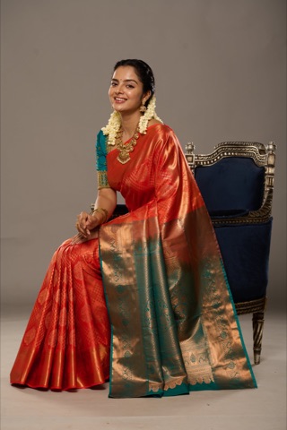 Woman in a red and green sari seated on an ornate chair