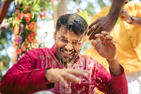 Man laughing as water is poured over him during a celebration