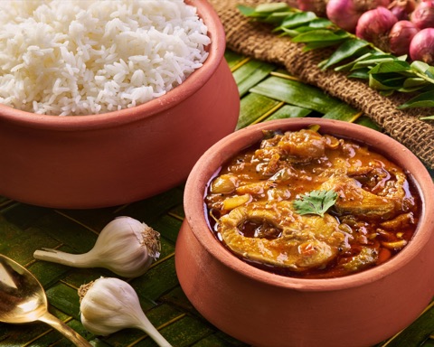 Curry and white rice in clay bowls with fresh ingredients