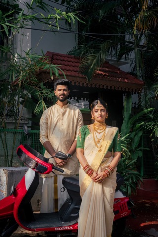 Couple in cream and green outfits beside a red scooter