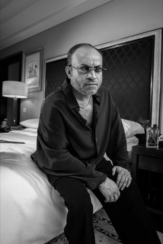 Black-and-white portrait of a seated man wearing glasses