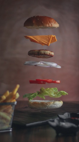 Burger ingredients suspended in layers against a dark backdrop
