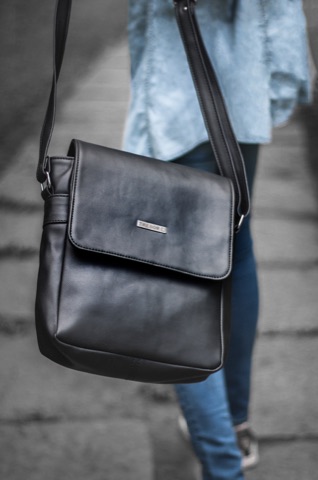 Black leather shoulder bag worn across a person's body