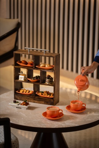 Tea being poured beside a tiered stand of savoury bites