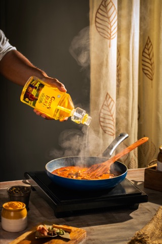 Cooking oil being poured into a hot pan of food