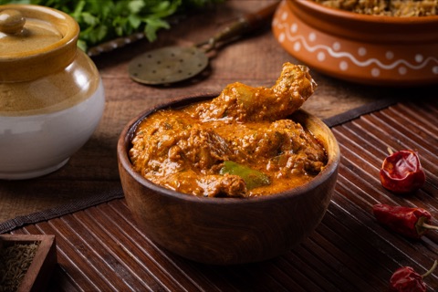 Chicken curry in an earthenware bowl with a drumstick