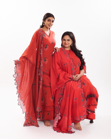 Two women modelling matching red outfits against white