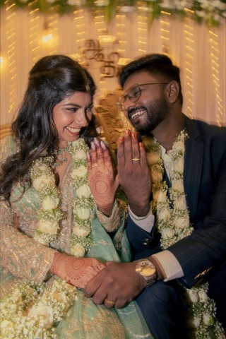 Couple laughing together while wearing white flower garlands