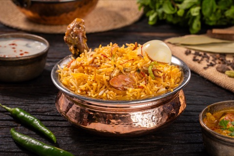 Biryani with a chicken drumstick and egg in a metal bowl