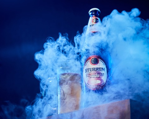 Glass drinks bottle and tumbler surrounded by blue-lit smoke