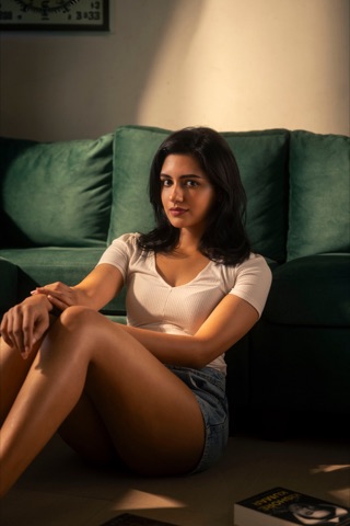 Woman seated on the floor beside a green sofa