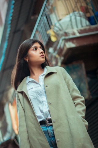 Woman in a pale green coat standing on an urban street