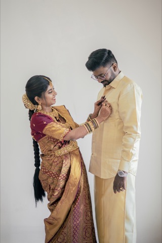 Full-length portrait of a woman adjusting a man's cream shirt