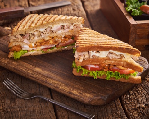 Toasted club sandwich halves on a rustic wooden board