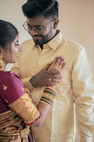 Woman adjusting a man's cream shirt during wedding preparations