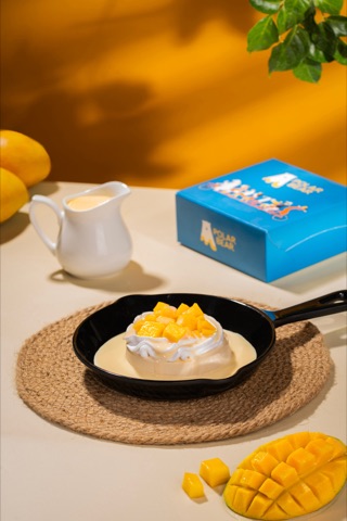 Mango-topped dessert on a black plate against a yellow backdrop