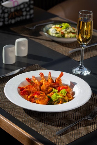 Prawns with vegetables on a white plate at a restaurant table