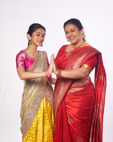 Woman and girl in bright traditional outfits posing together