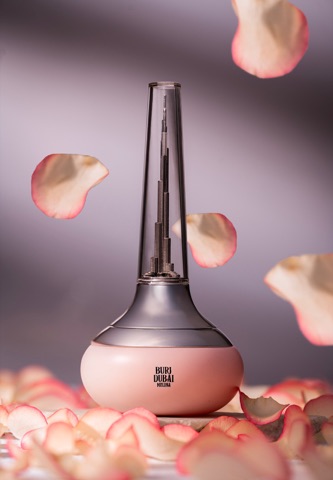 Pink perfume bottle with a tall metallic cap among rose petals