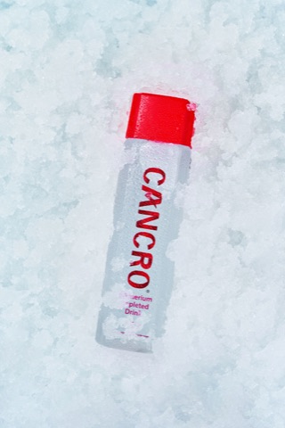 Clear bottle with a red cap resting on crushed ice
