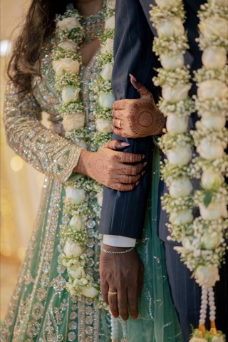 Close-up of a couple's hands and flower garlands