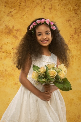 Girl in a white dress and flower crown holding a bouquet