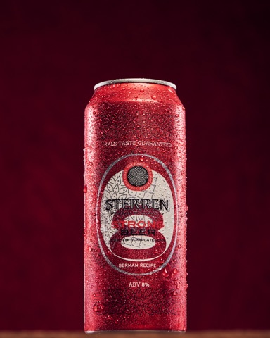 Condensation-covered red drinks can against a dark red backdrop