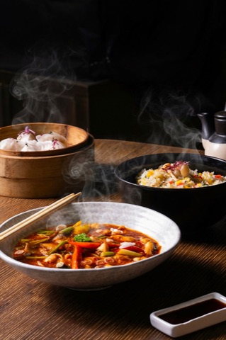Steaming dishes served with rice and dumplings on a dark table