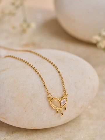 Delicate gold-coloured necklace on pale curved display blocks