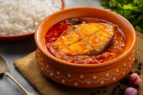 Fish curry in a clay bowl beside white rice