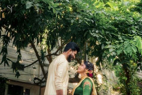 Couple facing each other beneath leafy branches