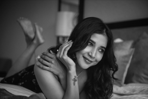 Black-and-white portrait of a woman resting on a bed