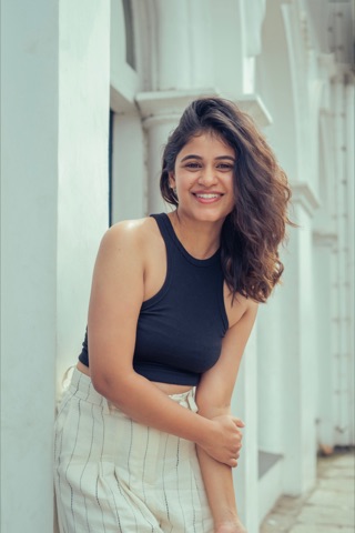 Smiling woman in a dark sleeveless top leaning by a window